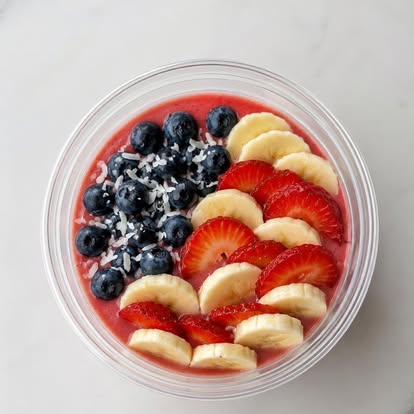 An açaí bowl topped with blueberries, strawberries, banana, and coconut